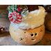 This shows the decorations on the elf hat. It features snowy red berries, pinecones, a candy cane button, and faux fur trim around the hat.